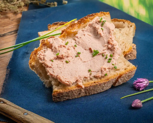 Leytmeyrhof Sreichwurst auf Brot mit Schnittlauch dekoriert Untergrund blau und Holz